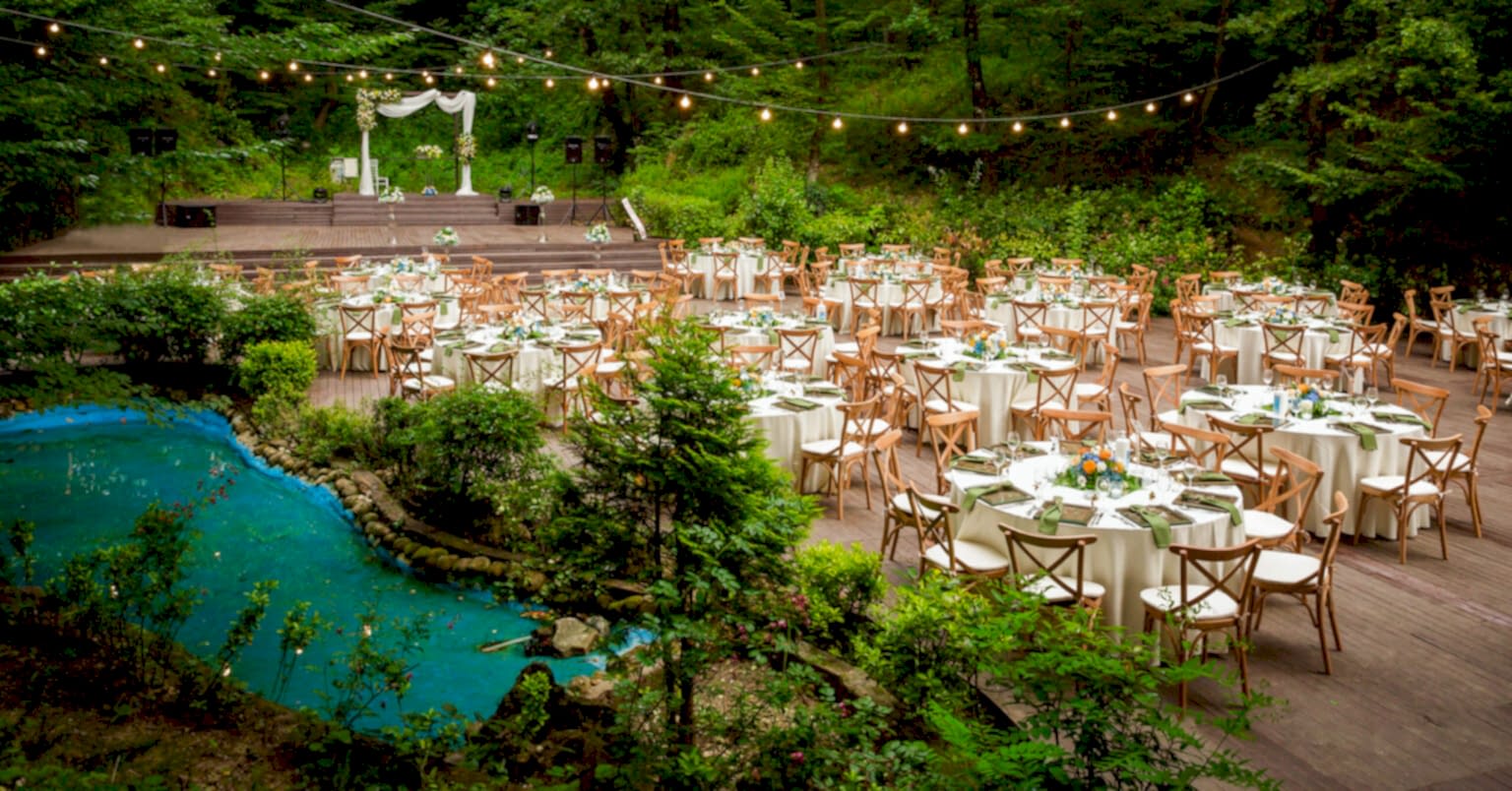 Kır düğünü konsepti için çiçeklerle süslenmiş, ahşap zeminli davet alanı.